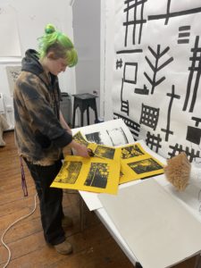 A young artist sorts through prints in their studio