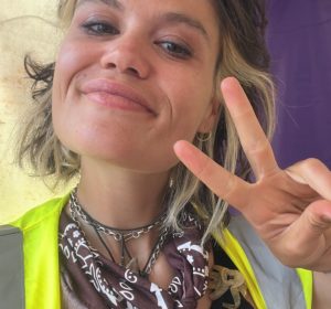 Headshot of a woman smiling and giving the peace sign